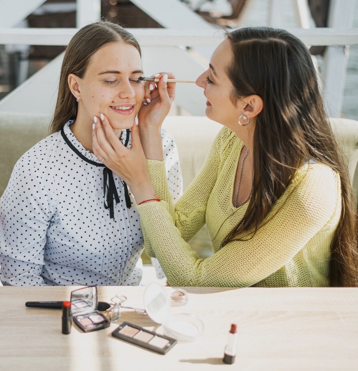Beauty school student applying makeup to a model during cosmetology training